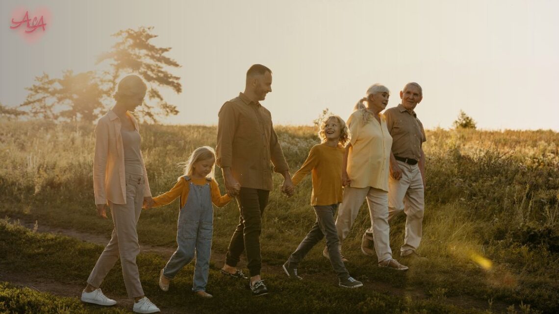 Uma grande família multigeracional sorrindo e se abraçando em um piquenique, com crianças de diversas idades, simbolizando o apoio da família extensa na adoção.