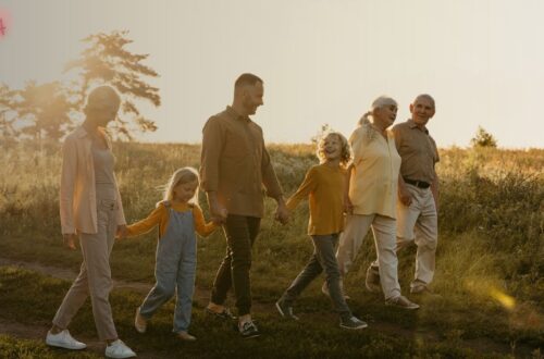 Uma grande família multigeracional sorrindo e se abraçando em um piquenique, com crianças de diversas idades, simbolizando o apoio da família extensa na adoção.
