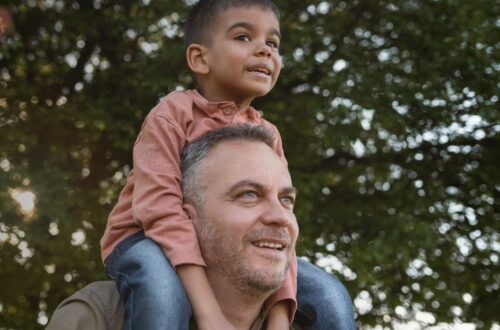 Um adulto solteiro (pode ser uma mulher ou um homem) abraçando uma criança com carinho, simbolizando a adoção uniparental e o amor familiar.